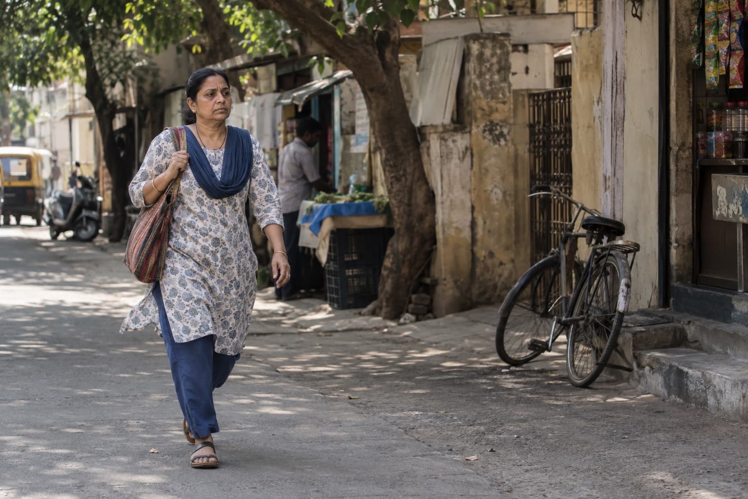 An Indian woman walks through a shaded city lane on her way to work