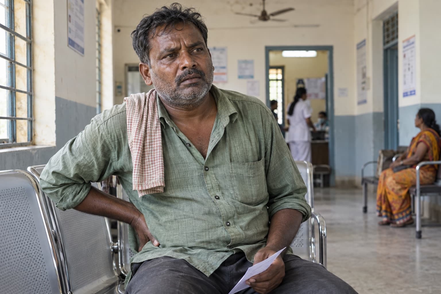 An Indian man with fever and side pain waits for an in-person clinic assessment